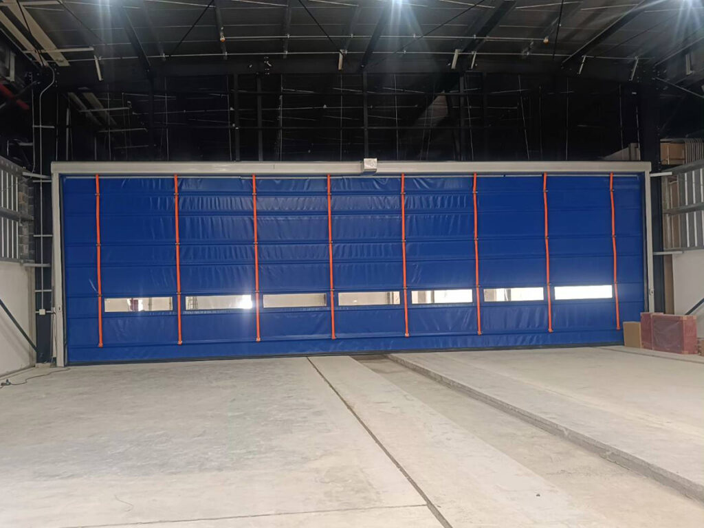 ประตูไฮสปีดแบบพับ ติดตั้งที่ช่องเปิดภายนอกคลังสินค้าขนาดใหญ่ โดย OZ Door Thailand