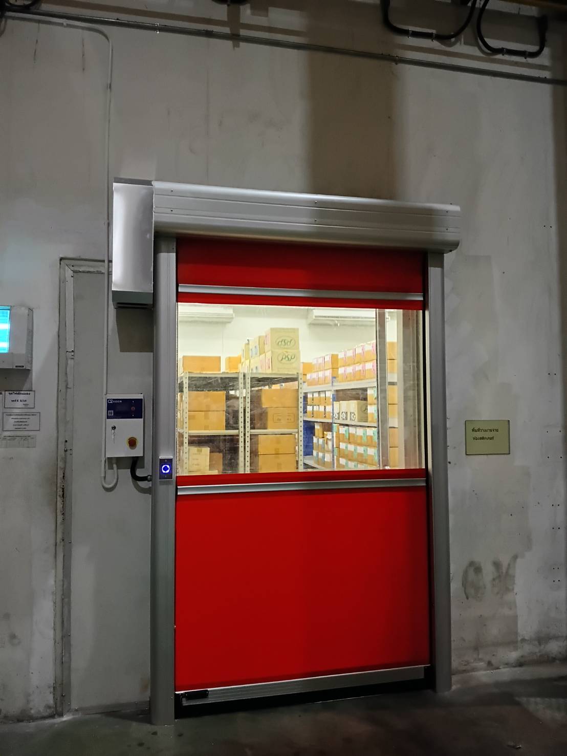 Red curtain with a vision panel in front of a shelved storage room