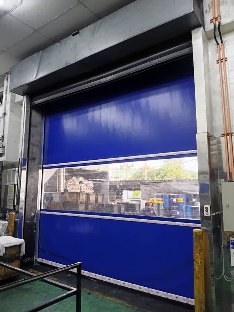 Reverse view of the blue door with wall pipes and protective posts