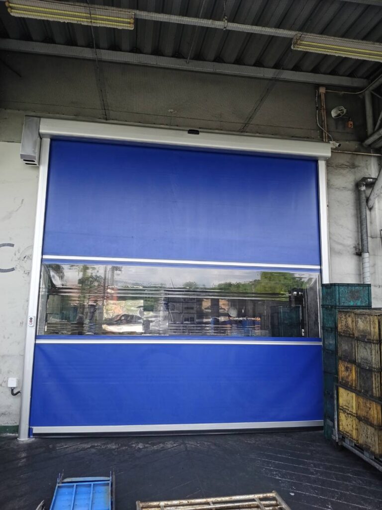 Wide blue high-speed door with a clear strip and left-side drive
