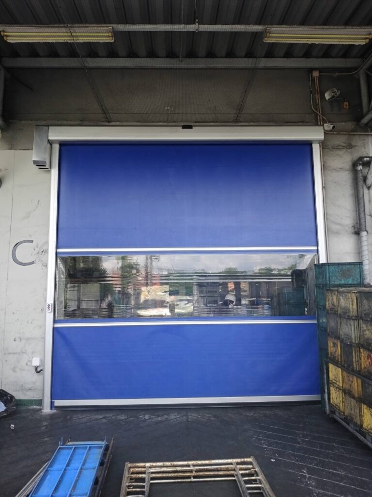 Full view of the wide blue-curtain door beneath the roof
